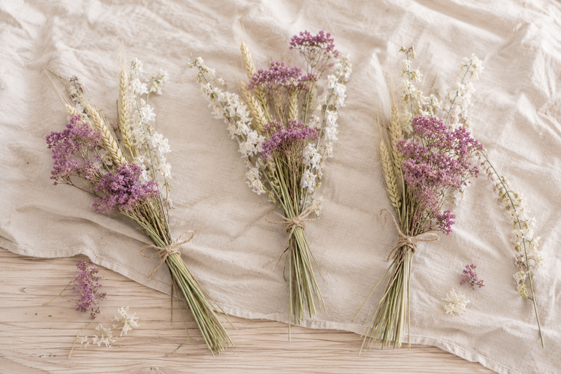 Mini bouquets de fleurs séchées composés d’achillée rose, de delphinium blanc et de blé.