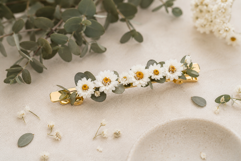 Barrette en fleurs séchées d'ammobium et eucalyptus parvifolia portée dans un chignon, idée de coiffure naturelle et élégante.