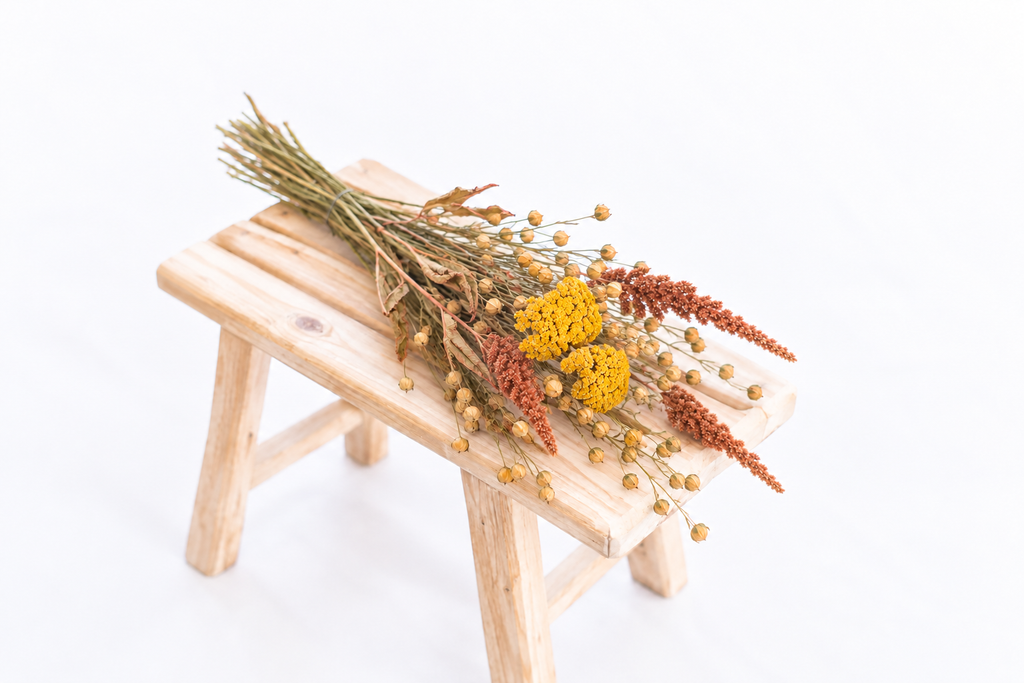 Botte composée d’achillée jaune, de lin et d’amarante Hot Biscuits posée sur un banc en bois