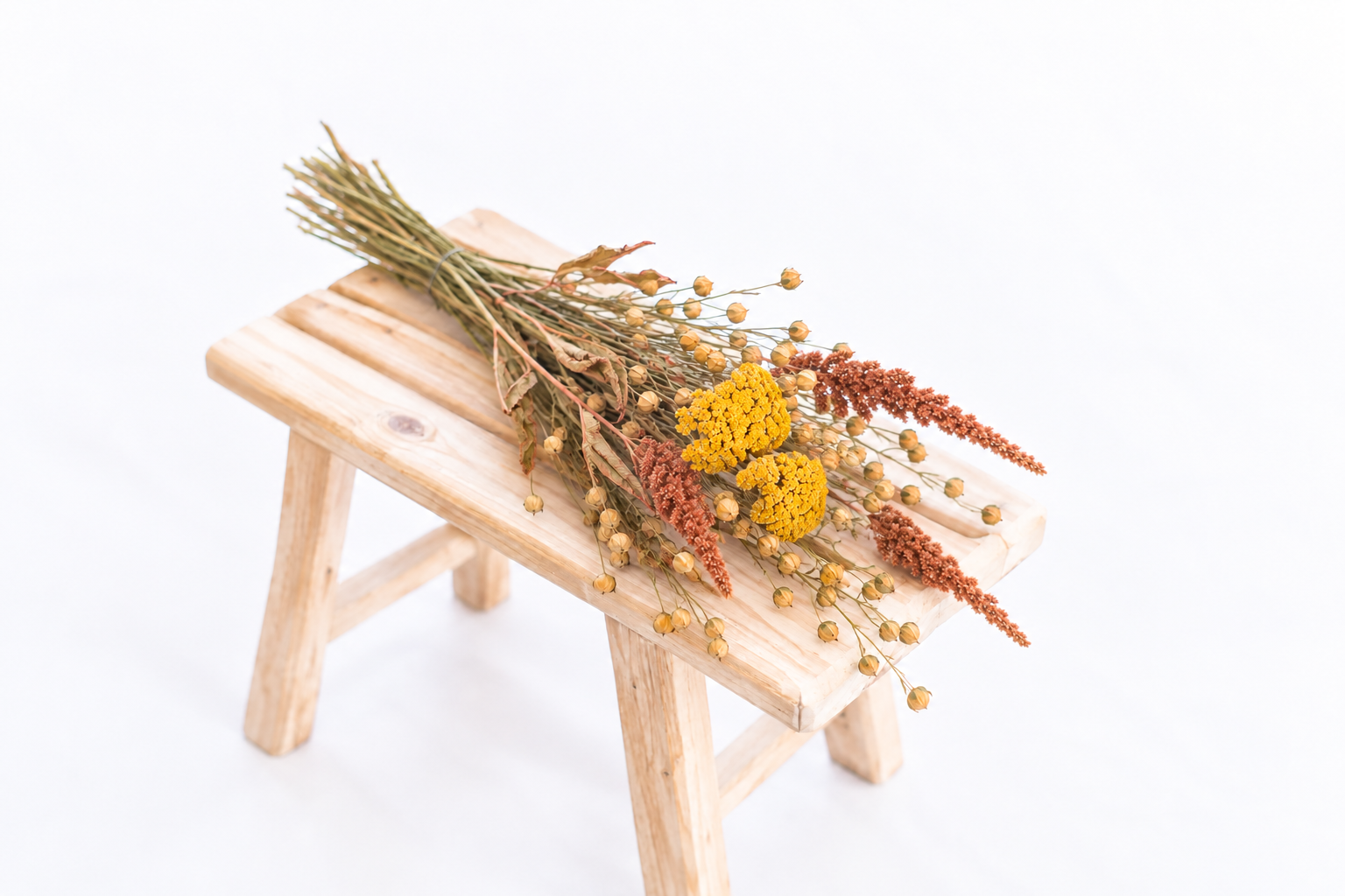 Botte composée d’achillée jaune, de lin et d’amarante Hot Biscuits posée sur un banc en bois