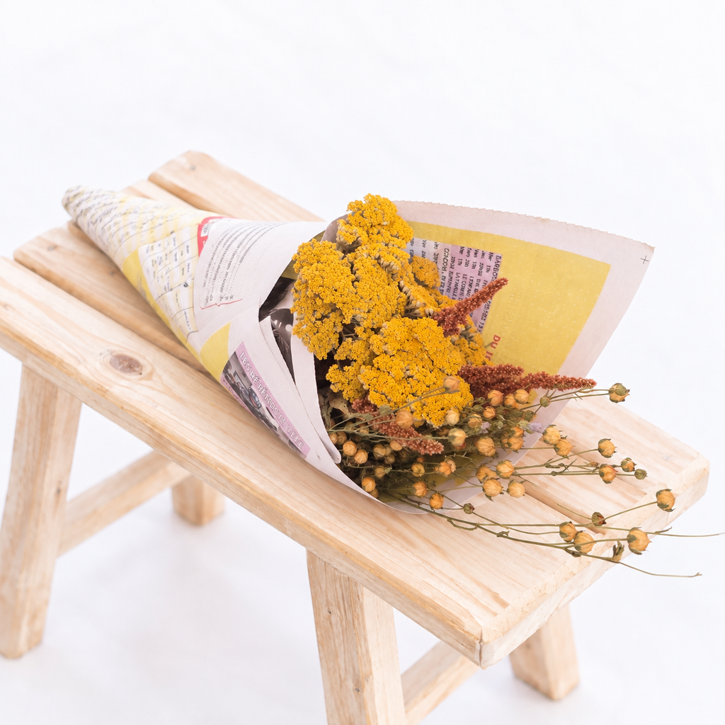 Botte composée d’achillée jaune, de lin et d’amarante terracotta emballée dans du papier recyclé