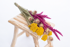 Botte composée de fleurs séchées avec achillée jaune, nigelle et fleur de pays cyclamen sur un banc en bois clair