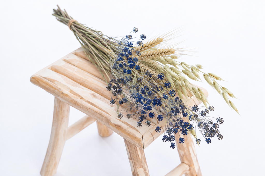 Botte composée de fleurs séchées avec ammi bleu, blé et avoine sur un banc en bois clai