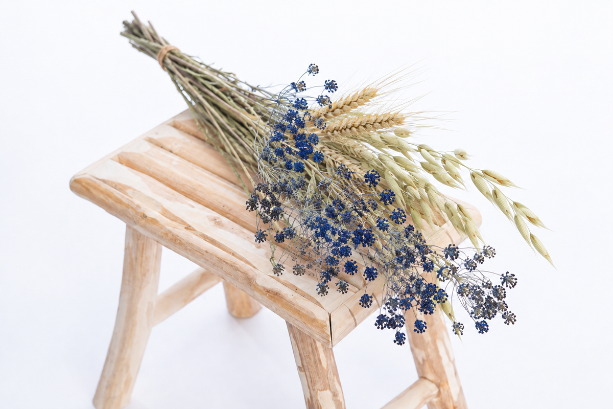 Botte composée de fleurs séchées avec ammi bleu, blé et avoine sur un banc en bois clai
