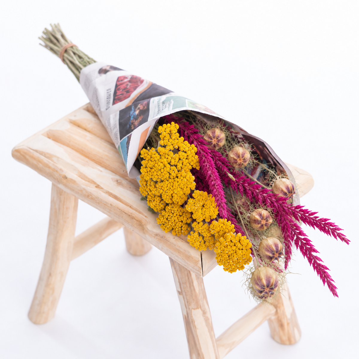 Botte composée d’achillée jaune, de nigelle et de fleur de pays cyclamen emballée dans du papier réemployé