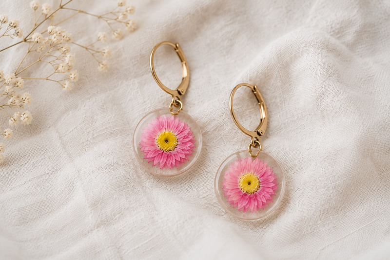 Boucles d'oreilles en résine avec fleurs séchées d'acroclinium rose, réalisées à partir de véritables fleurs naturelles françaises.