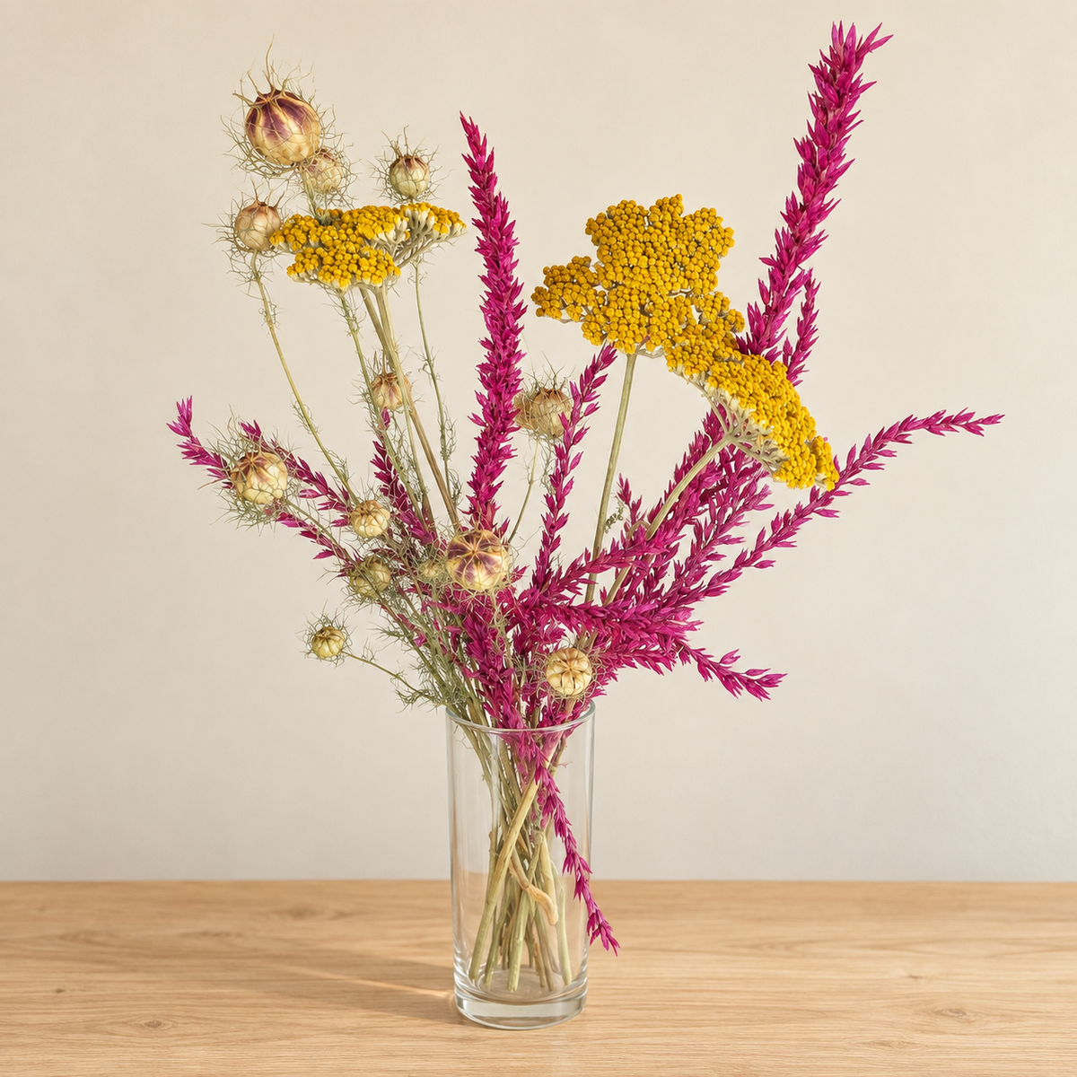 Bouquet de fleurs séchées composé d’achillée jaune, de nigelle et de fleur de pays cyclamen dans un vase clair