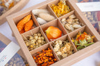 Coffret Tons orangés Terralya ouvert, présentant neuf compartiments de têtes de fleurs séchées, avec phalaris orange, lagurus, physalis, lin et carthamus.