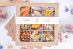 Coffret Terralya de têtes de fleurs séchées aux tons orangés, présenté fermé avec son bandeau, contenant neuf compartiments de fleurs françaises bio.