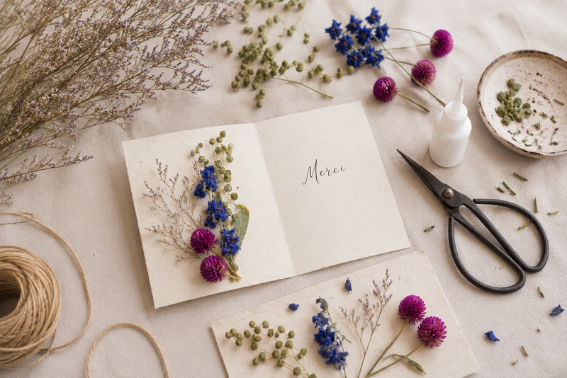 Carte de remerciement décorée de fleurs séchées avec delphinium bleu, limonium latifolium, cresson et gomphrena violette.