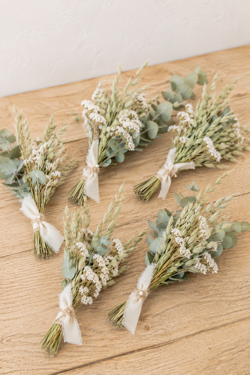 Mini bouquets de mariage en avoine séchée, statice blanc et eucalyptus, réalisés avec des fleurs séchées françaises pour une décoration bohème naturelle.